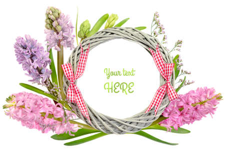 Round frame with pink and purple hyacinth flowers and checkered bows on white background. Space for your text. Shallow DOF, focus on the straw wreath.の写真素材