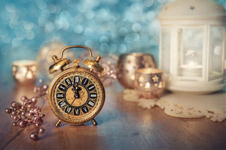 Old alarm clock set to five to midnight on decorated table with candles. Happy New Year!の写真素材