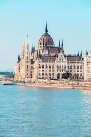 Parliament building in Budapest, Hungary, on a bright day across Danube, with unrecognizable people on the riverbank. This image is tonedの写真素材