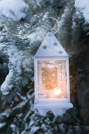 Little winter lantern hanging outdoors on a Christmas tree under snow. Merry Christmas! Shallow DOF,...
