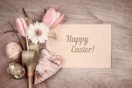 Easter arrangement with flowers and eggs on wood with caption "Happy Easter!"の写真素材