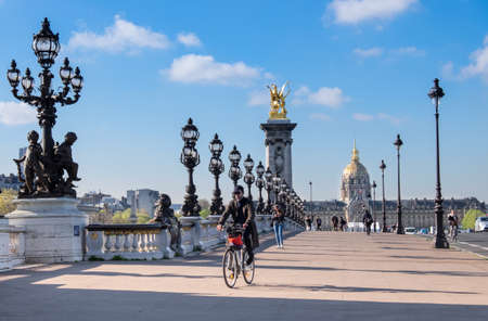 PARIS, FRANCE - APRIL 19 2016: Early morning pedestrians and cyclists on Alexandre Bridge in Paris on a bright sunny morning in Spring.のeditorial素材