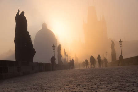 Spectators watch the dense fog on Charles Bridge on the bright Easter moring, as the Sun rises over the towers.の写真素材