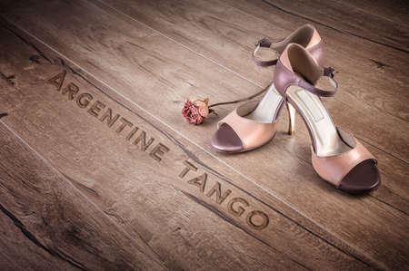 Argentine tango shoes and a dry rose on a wooden floor, caption "Argentine tango"の写真素材