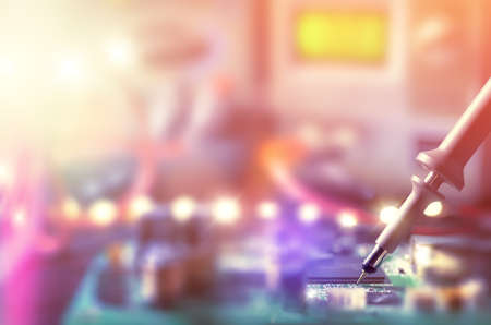 Closeup on electronic board in hardware repair shop, blurred and toned image. Shallow DOF, focus on the tester tool on the right, space for your textの写真素材