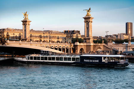 PARIS, FRANCE - APRIL 19 2016: Passenger boat passed under Alexandre Bridge in Paris on a sunset. Paris is the most popular touristic destination in the world.のeditorial素材