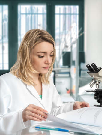 Young female scientist in the lab checks her laboratory journalの写真素材