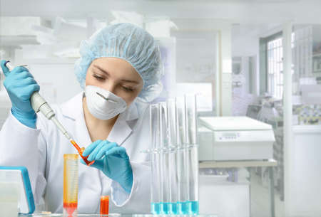 Young female tech or scientist loads liquid sample into test tube with plastic pipette. Shallow DOF, focus on the eyes and hands.の写真素材