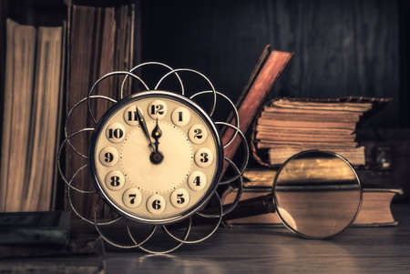Vintage alarm clock showing five to twelve among old books in a study room. This image is toned. Space for your greeting. Happy New Year 2017!の写真素材