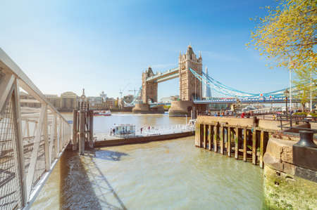 LONDON, UK- APRIL 16, 2014: Passengers waiting on the pier for a boat on a sunny day in Spring with Tower Bridge as a backdrop. This image is toned.のeditorial素材