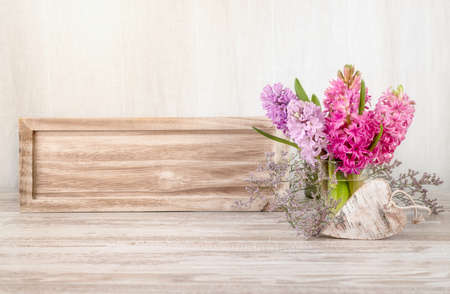 Spring arrangement with hyacinth flowers and wooden heart. Text space on the wooden board. This image is toned.の写真素材