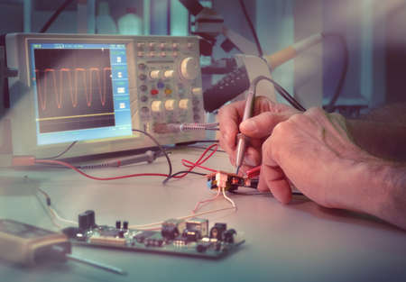 Senior male engineer or tech tests electronic equipment in hardware service centre. This picture is toned.の写真素材