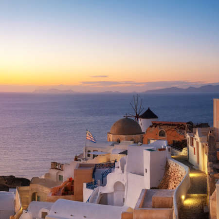 Beautiful Santorini in Greece - traditional windmill and apartments in Oia village after sunset, panoramic image.のeditorial素材