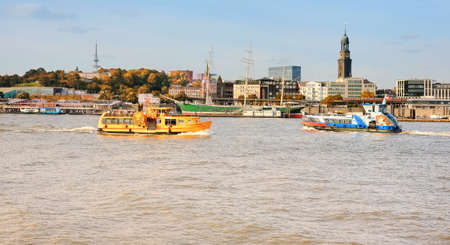 HAÃï¿½BURG, GERMANY- AUGUST 12, 2015: Boat with tourists goes on Elbe river in Hamburg with St. Michael church spire visible.のeditorial素材