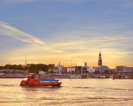 HAMBURG, GERMANY- AUGUST 12, 2015: Boat with tourists goes on Elbe river in Hamburg on a sunsetのeditorial素材
