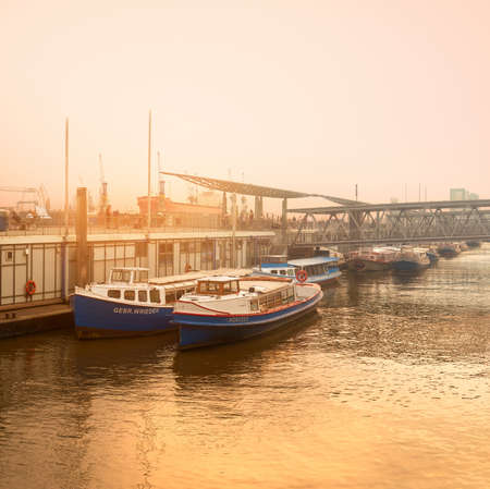 HAMBURG, GERMANY- AUGUST 14, 2015: Sunset in Hamburg on a misty evening by Elbe river with towed passenger boats, toned panoramic imageのeditorial素材