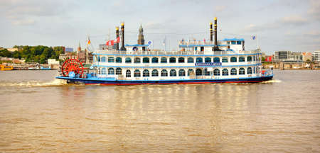 HANBURG, GERMANY- AUGUST 12, 2015: Louisiana Star rear wheel steamer full of tourists goes on Elbe river in Hamburg, Germany. Panoramic image.のeditorial素材