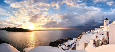 Sunset over Santorini island in Greece. Traditional church, apartments and windmills in Oia village on a sunset, panoramic image.のeditorial素材