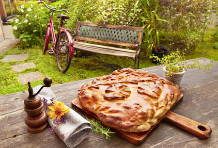 Homemade Russian pie, yeast bun with hardy filling, on the garden table outdoorsの写真素材