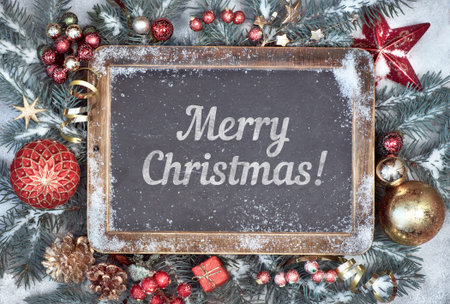 Blackboard with text Merry Christmas with Christmas decorations on snow. Top view, toned image