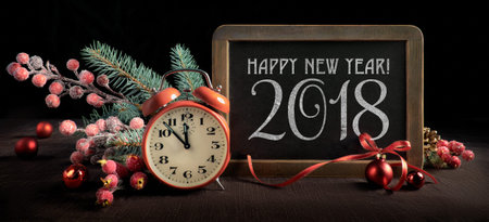 Blackboard with text A Happy New Year 2018 with alarm clock and winter decorations on black...
