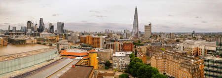 A high angle view of the cityscape and skyscrapers of the old business and financial district, The City of London. Panoramic image taken on a gloomy day with overcast sky. Toned image.の写真素材