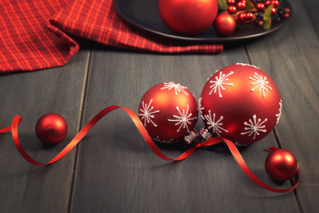 Red Christmas baubles tied with ribbon and red napkin on wooden tableの写真素材