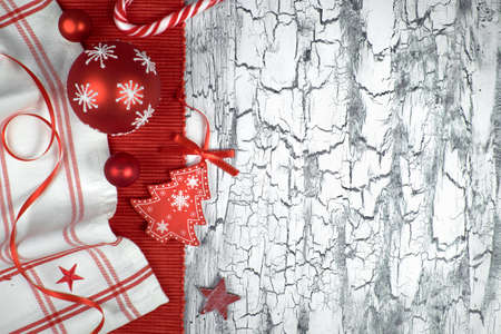 Red Christmas baubles with napkins, ribbons and a candy cane on a rustic neutral background, space for your textの写真素材