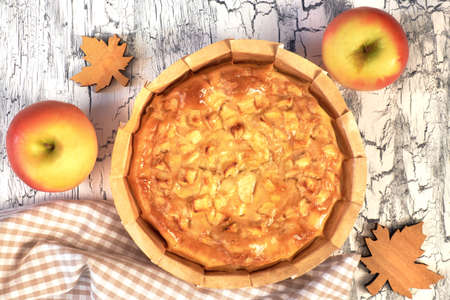 Homemade apple pie with apples, berries and linen napkin on light rustic background. Top view, toned image.の写真素材