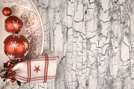 Decorative plate with red Christmas baubles and napkin with napkin ring on rustic neutral...
