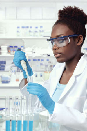 African-american scientist or graduate student in lab coat and protective wear works in modern laboratoryの写真素材