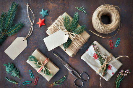 Hand crafted gifts on dark background with Christmas decorations. Seasonal background shot from above. Flat lay, top view, filtered image. Tag mockup, copy space on the tags.の写真素材
