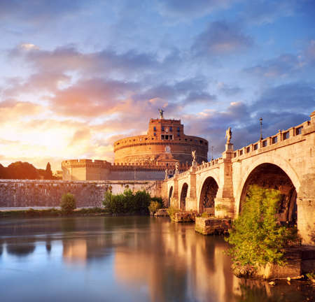 Saint Angelo Castle and bridge over the Tiber river in Rome, Italy, at sunsetの写真素材