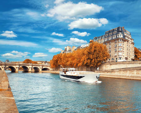 Passenger boat passes Pont Neuf on Seine river in Autumnの写真素材