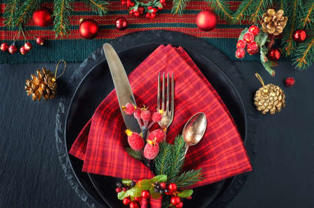 Christmas menu concept on dark background. Black plates and vintage cutlery with Christmas decorations in green and red. の写真素材