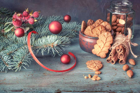 Christmas arrangement with almond leaf cookies in green and red and on rustic wooden tableの写真素材