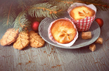 Christmas time, closeup on almond cookies and lemon mini-muffin with almonds, brown sugar, baubles and Christmas tree twigs on rustic wooden backgroundの写真素材