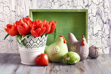 Easter composition with red tulips, ceramic hens and Easter eggs on old cracked woodの写真素材