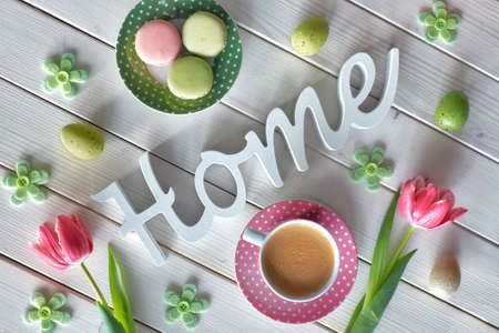 Spring coffee background. The word "Home" made of wood, pink tulips, espresso, macarons and Spring decorations, top view.の写真素材