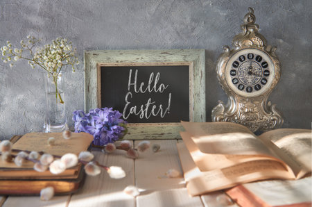Springtime background with an open book, blackboard with text Hello Easter and spring flowers. 