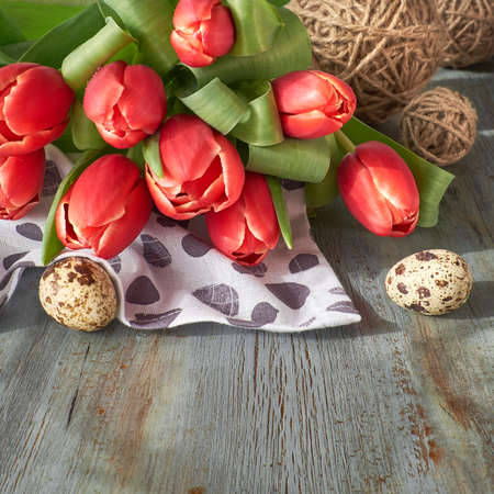 Spring celebration background: bunch of red tulips, spring decorations and painted eggs on gray rustic background, text spaceの写真素材