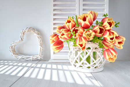 Springtime greeting card design with bunch of red tulips and spring decorations on light wooden backgroundの写真素材