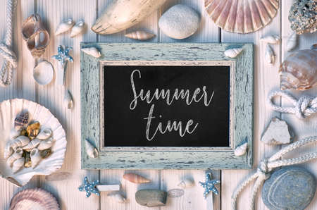 Blackboard with "Summer time" chalk text, with sea shells, rope and star fish on light wooden backgroundの写真素材