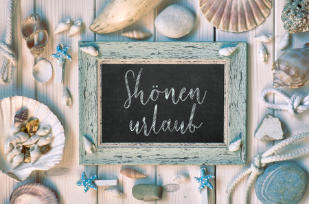 Blackboard With Maritime Decorations on light wood, text in German, "Shonen urlaub" Means "Happy holidays"の写真素材