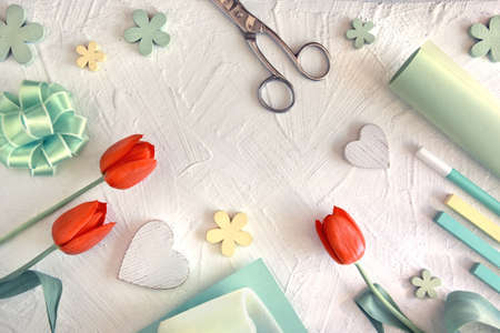 Spring holiday background with green and yellow decorations, wrapping paper, pegs and chalks on white textured backgroundの写真素材