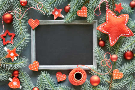 Christmas background with fir twigs, red trinkets, stars and hearts around blank blackboard. Top view with space for your text.の写真素材
