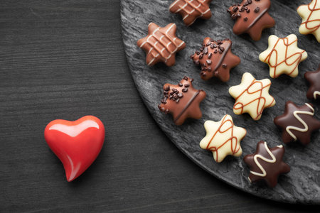 Star-shaped chocolates on dark textured background with red ceramic heart, Valentine or Christmas...