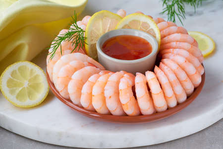 Close-up on shrimp ring with sweet chili sauce on marble serving board with yellow towel on light backgroundの写真素材
