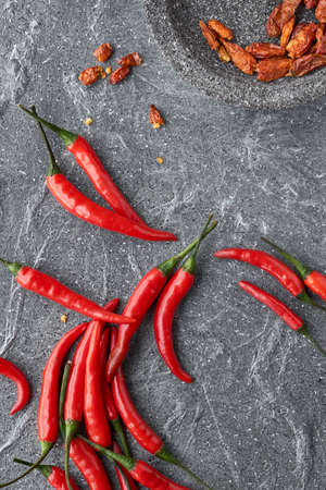 Close-up on red hot chili peppers, fresh and dry, on grey stone, top viewの写真素材
