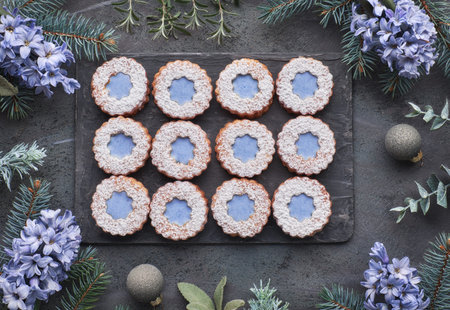 Top view of flower Linzer cookies with blue glazing on dark winter background in green decorated...